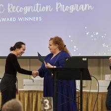 Woman receives recognition certificate on stage